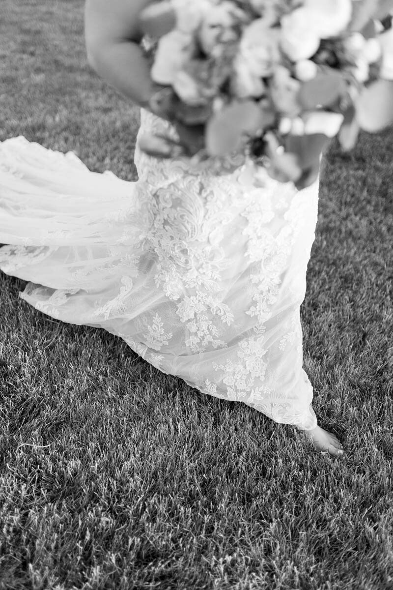 A bride walks barefoot through the grass.
