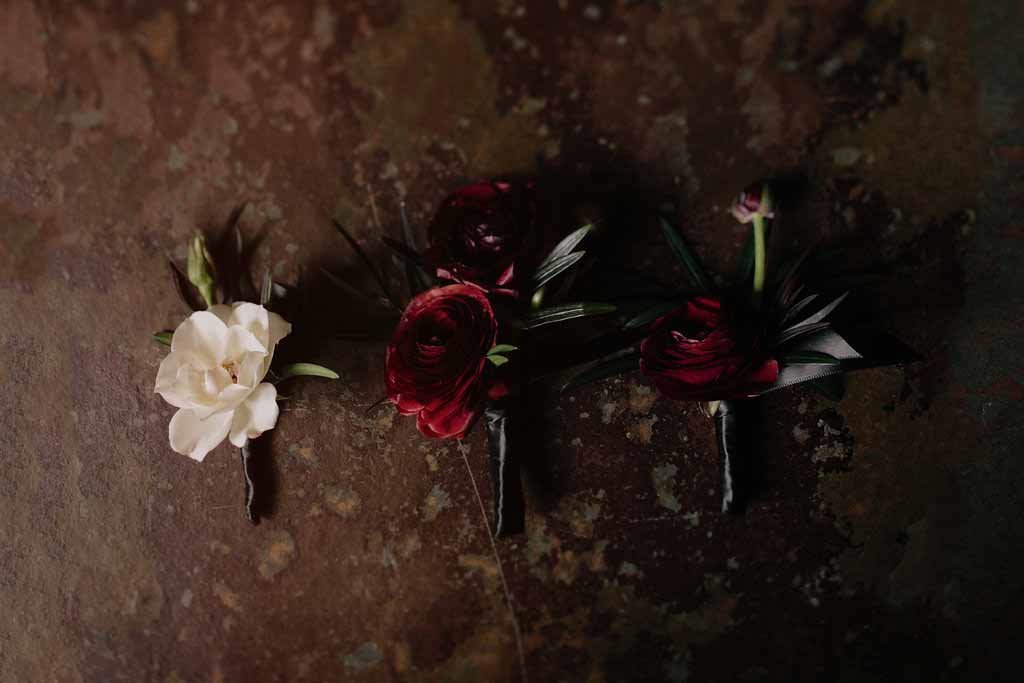 Boutonnieres of ranunculus wrapped with black ribbon.