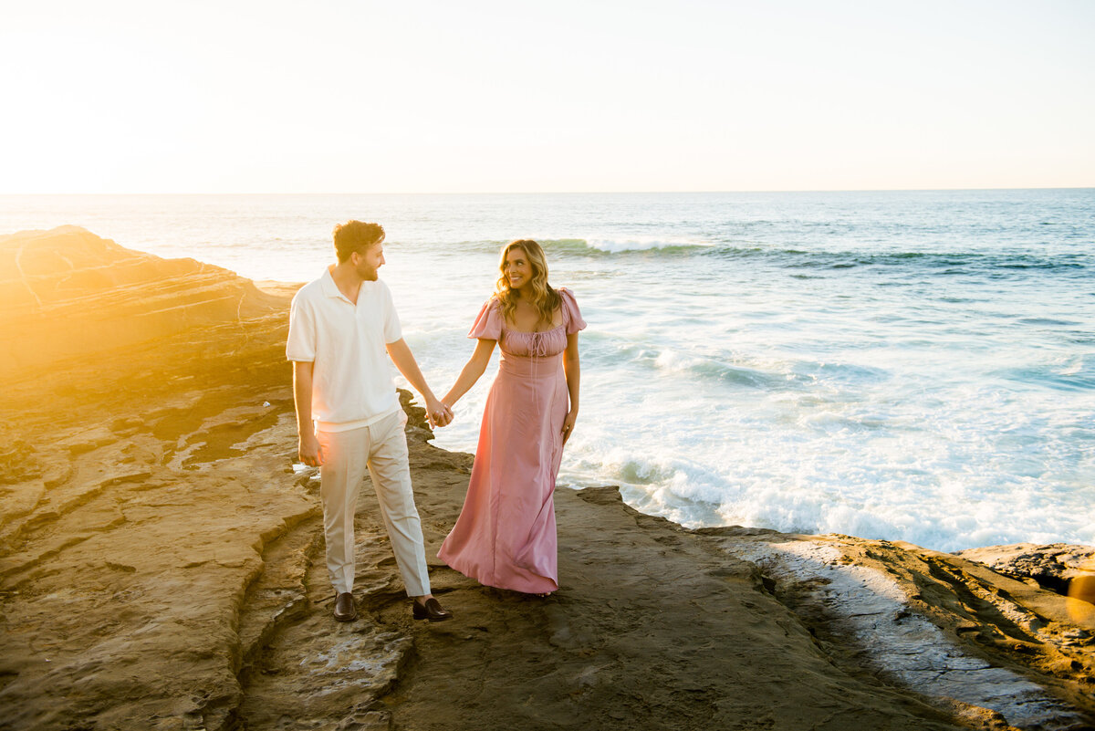 romantic couple walking along the cliffside in san diego during couples session with mattie taylor photography