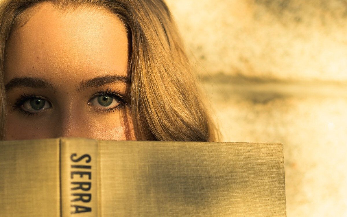Close-up  photo of a woman holding  a book close to the eyes