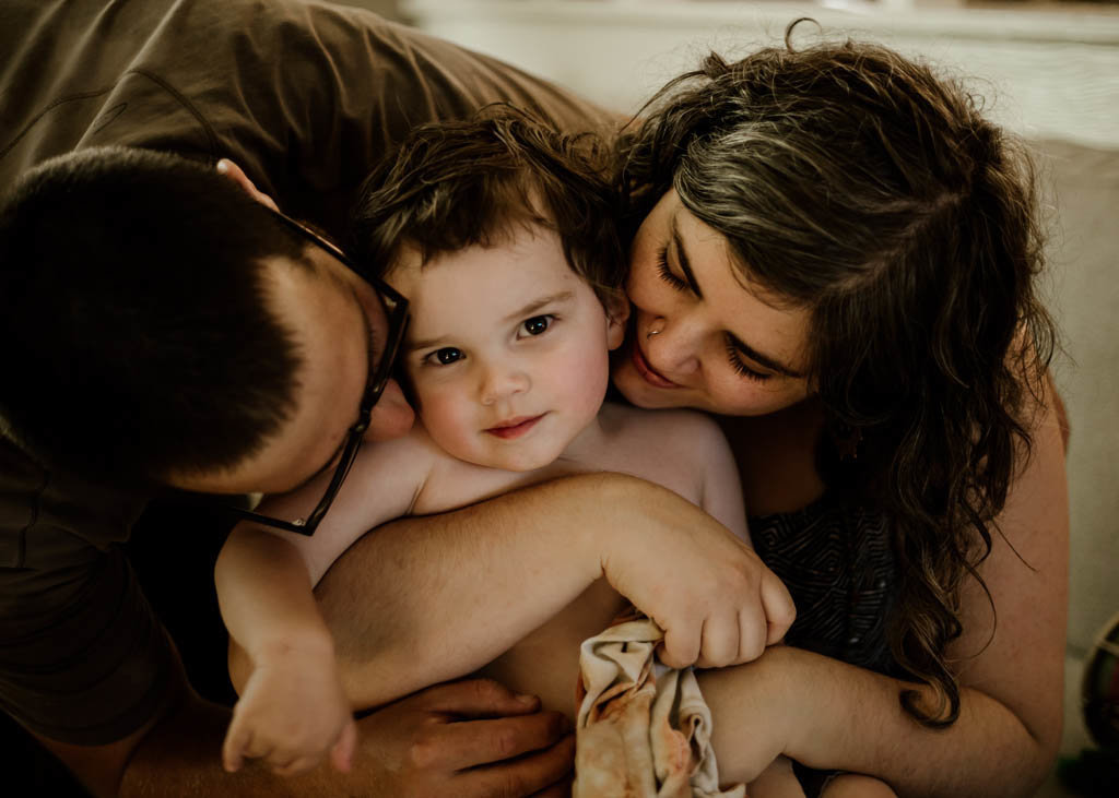 Bay area parents snuggle around son at in home family photography session