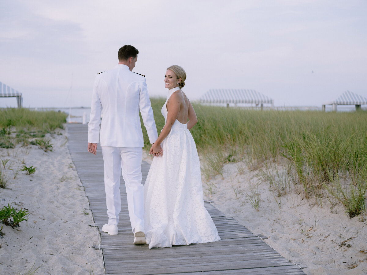 A wedding couple walks along the boardwalk of the Chatham Bars Inn beach