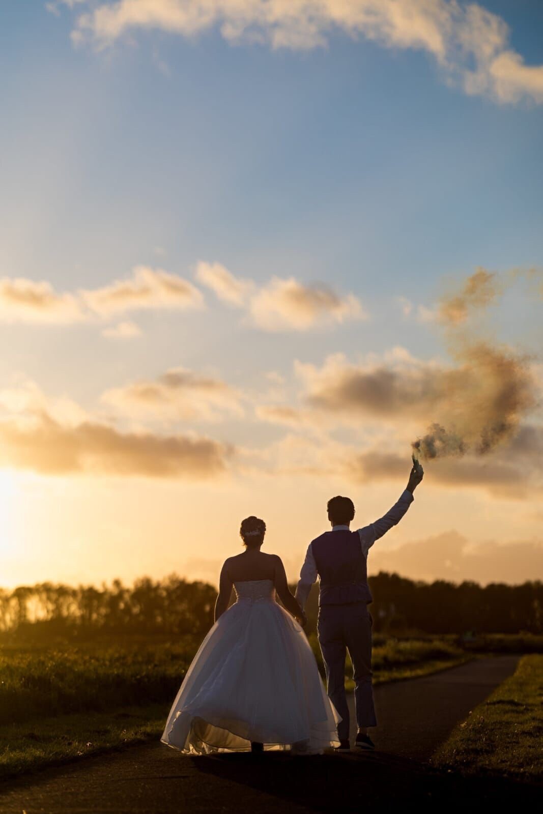 Bruidspaar loopt tijdens golden hour door prachtig gouden licht met fakkel in hand, perfect gepland door ceremoniemeester en weddingplanner