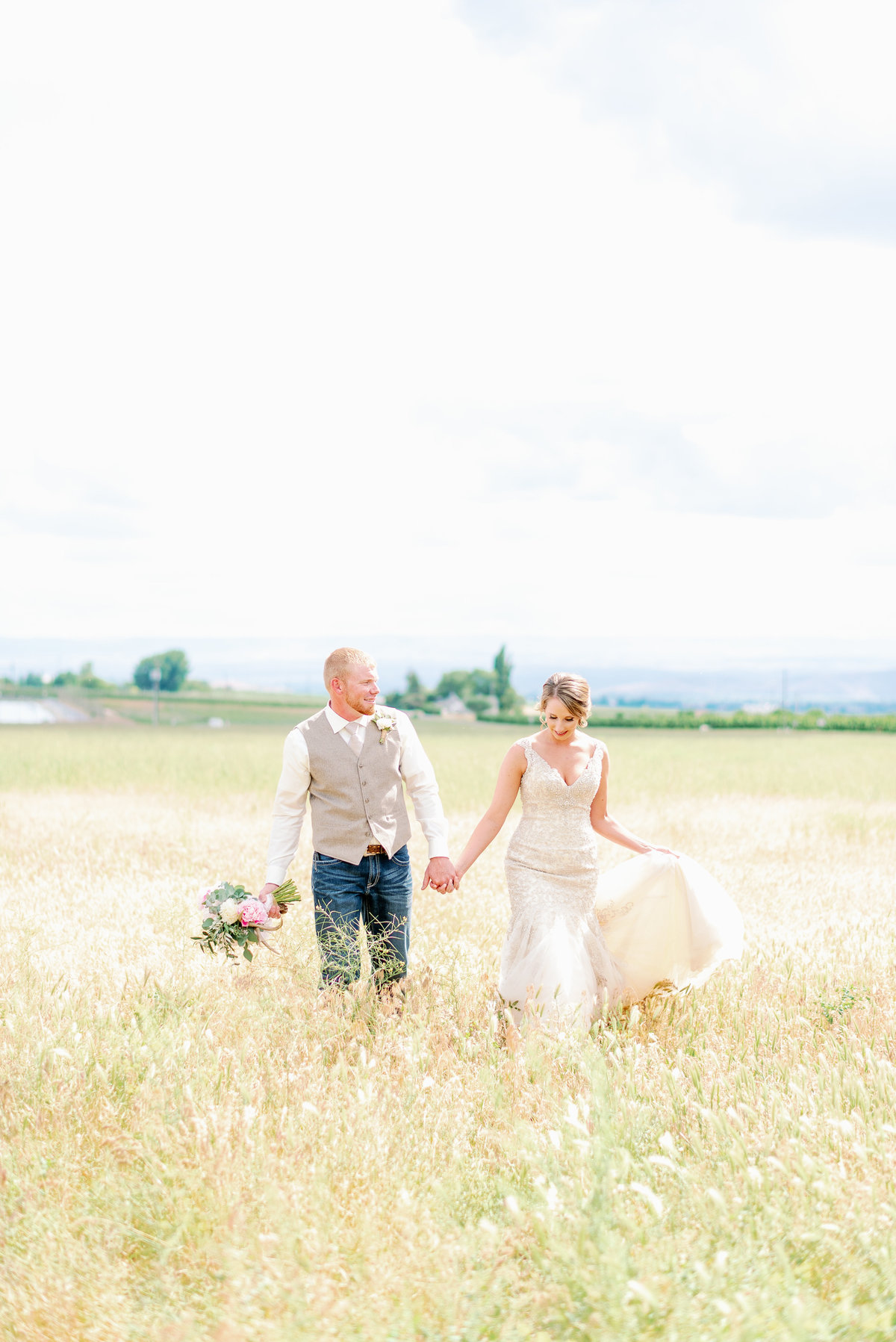 Bride and groom walking through field