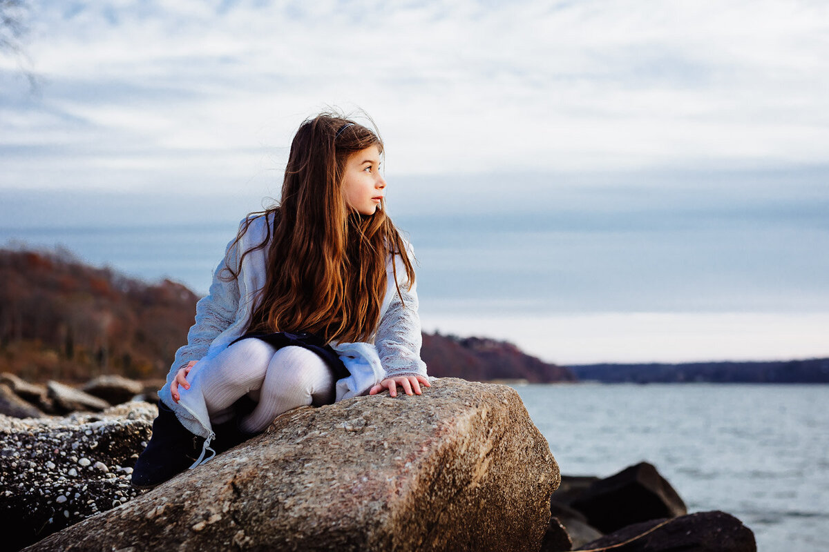 girl sitting on rocks during long island family photo shoot