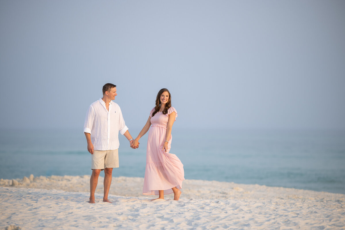 A couple holding hands and standing in the sand