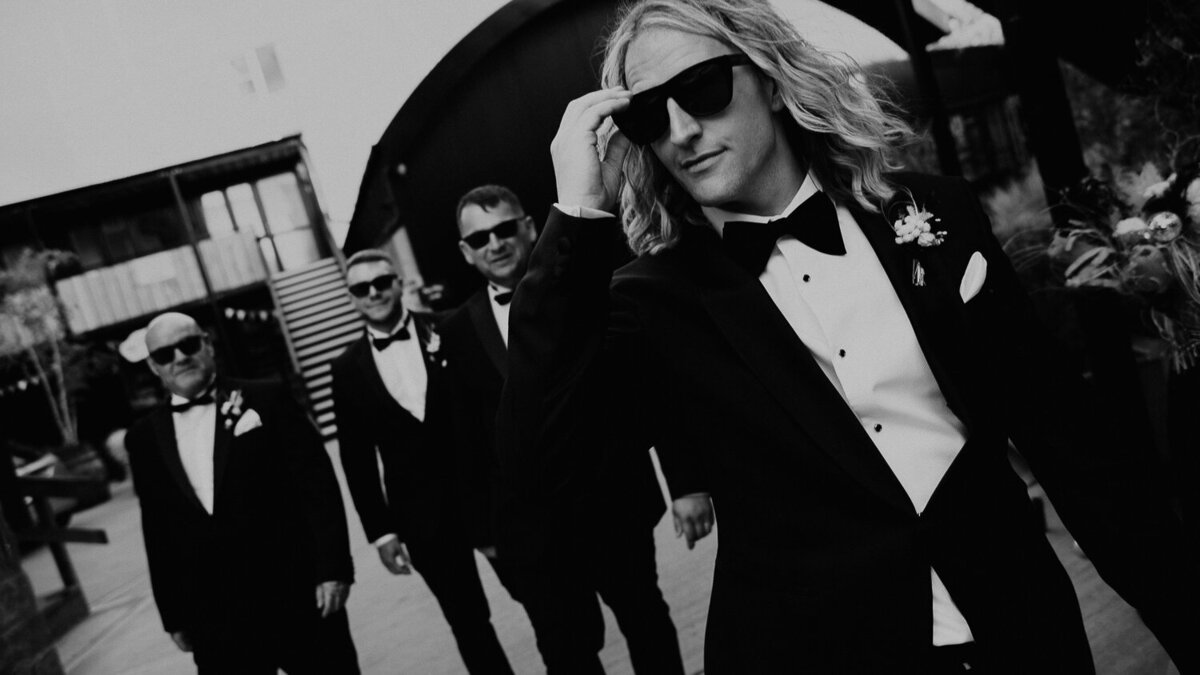 Groomsmen wearing sunglasses and black tie tux walking away from The Shack Revolution in Hereford. 