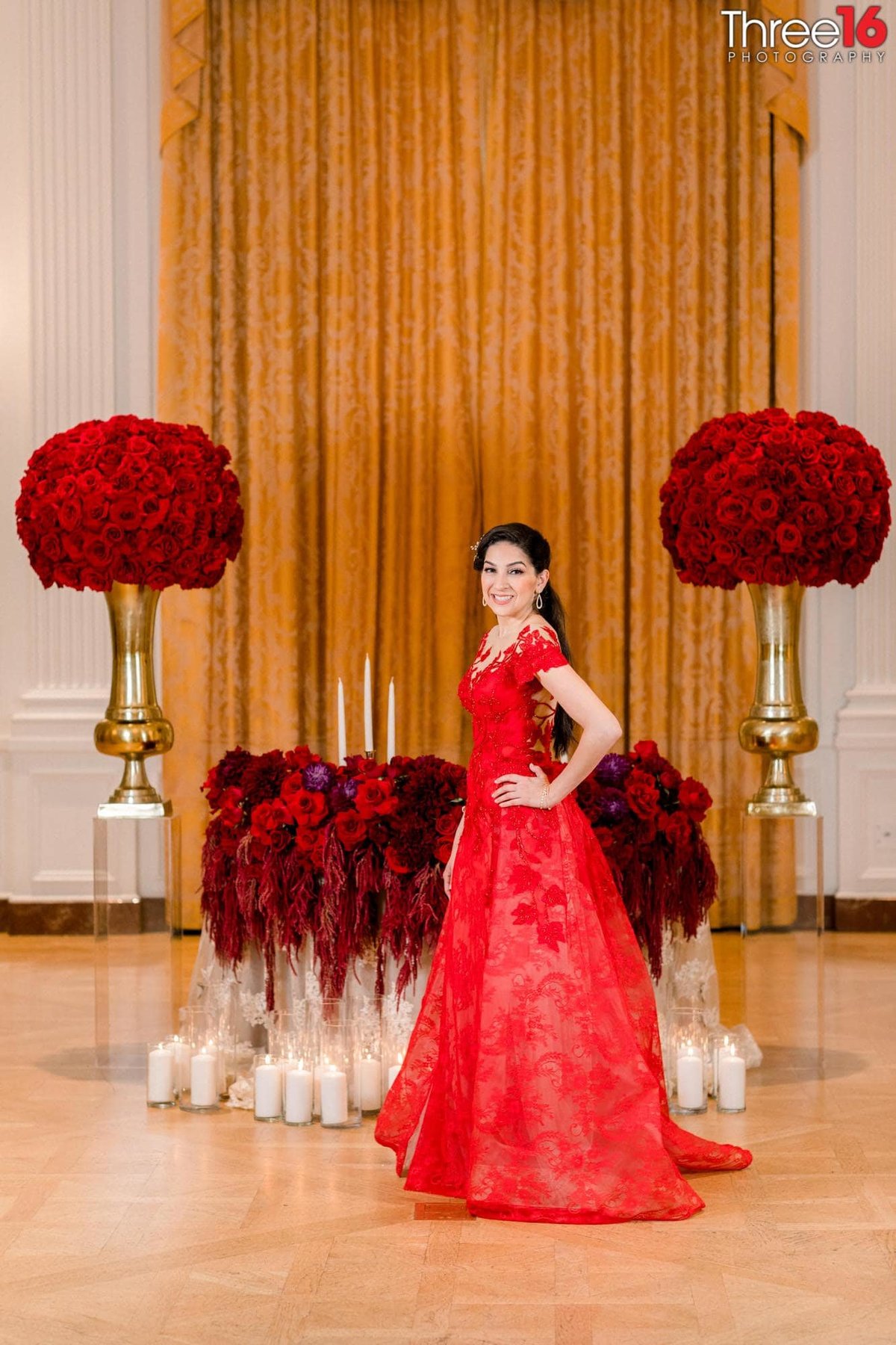 Bride dressed in a red dress stands in front of the sweetheart table
