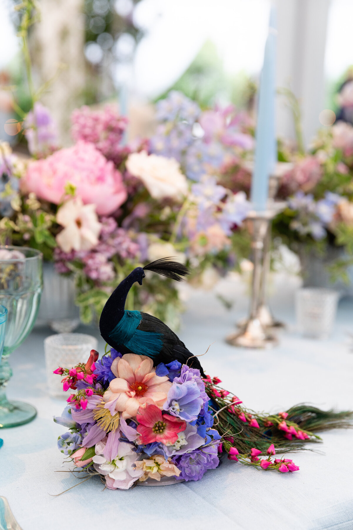 Growing, fresh floral centerpieces with a peacock, including blush garden roses, lilac, blue sweet peas, ranunculus, lavender delphinium, globe allium, and natural greenery for a tented Bridgerton inspired engagement party at a private home in Nashville, TN.