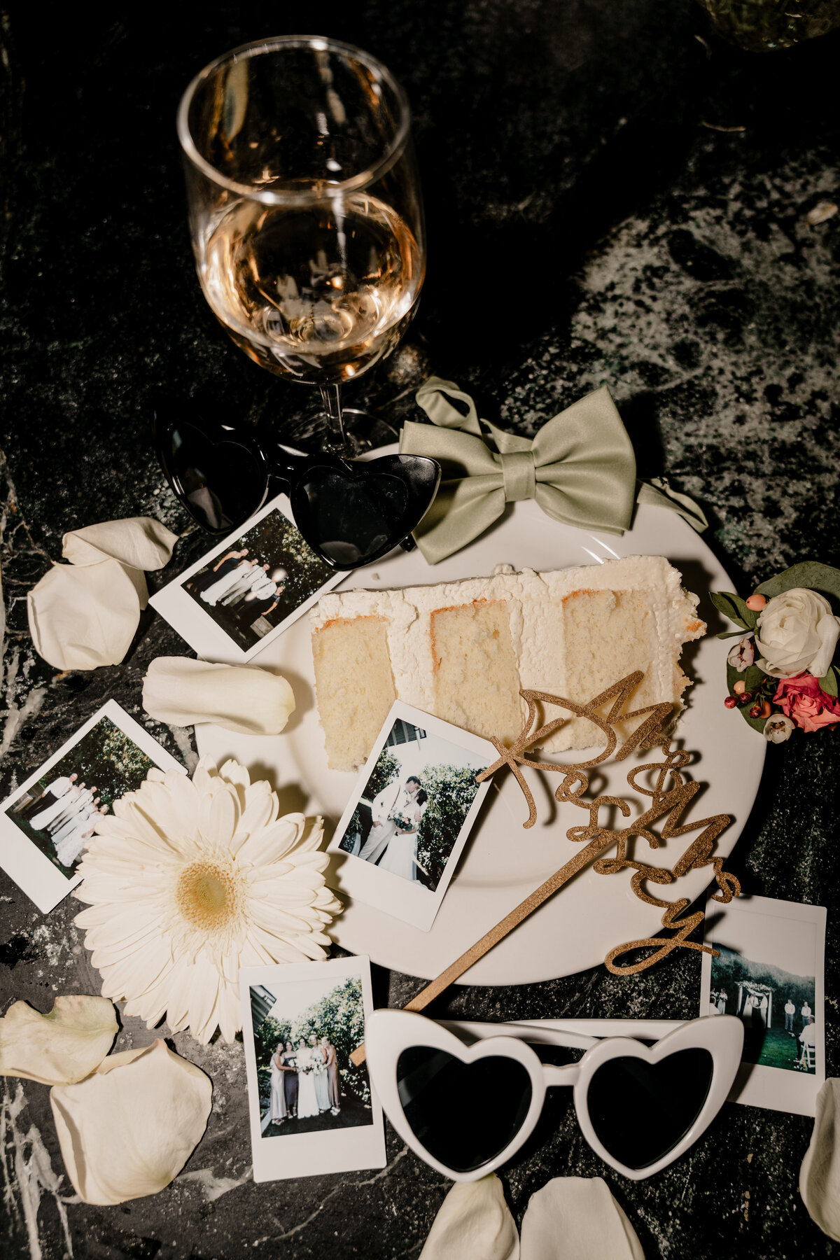 Flash photo of a slice of cake, polaroids, and a wine glass from the end of the wedding.
