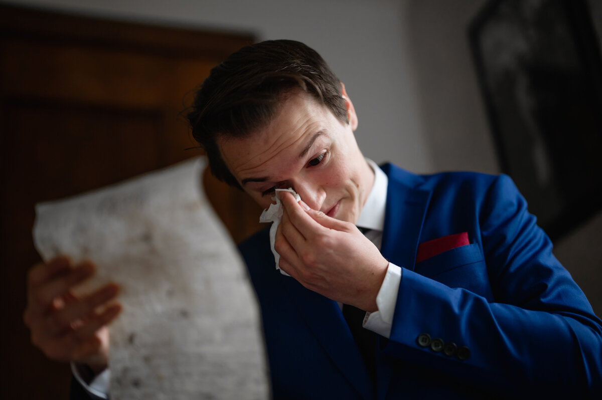 A groom in blue suit reads letter from his bride