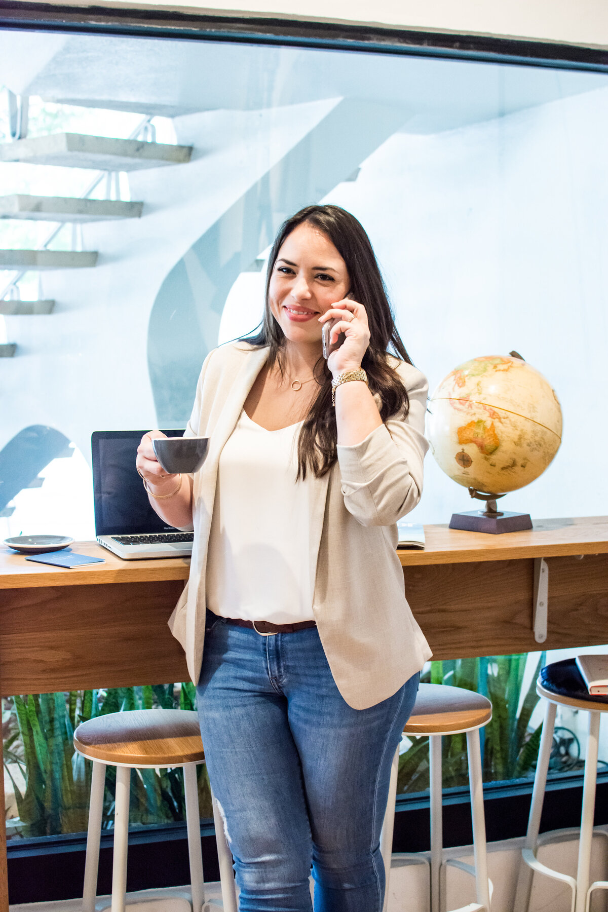 Smiling woman talking on cell phone holds a cup of coffee