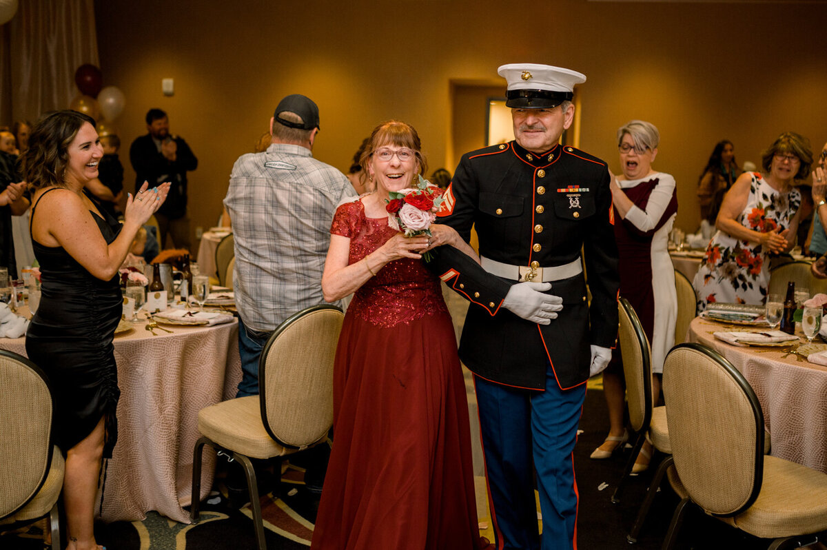 Bride and groom entering their 50th wedding anniversary reception as guests cheer in celebration.
