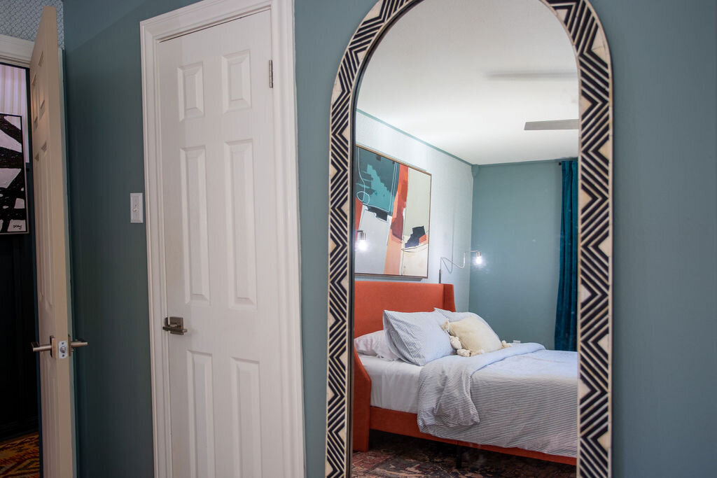 Large floor length mirror in the bedroom of this three-bedroom, two-bathroom mid-century house that sleeps 8 and boasts a unique experience in color, style, and lifestyle products located in the heart of Waco, TX.