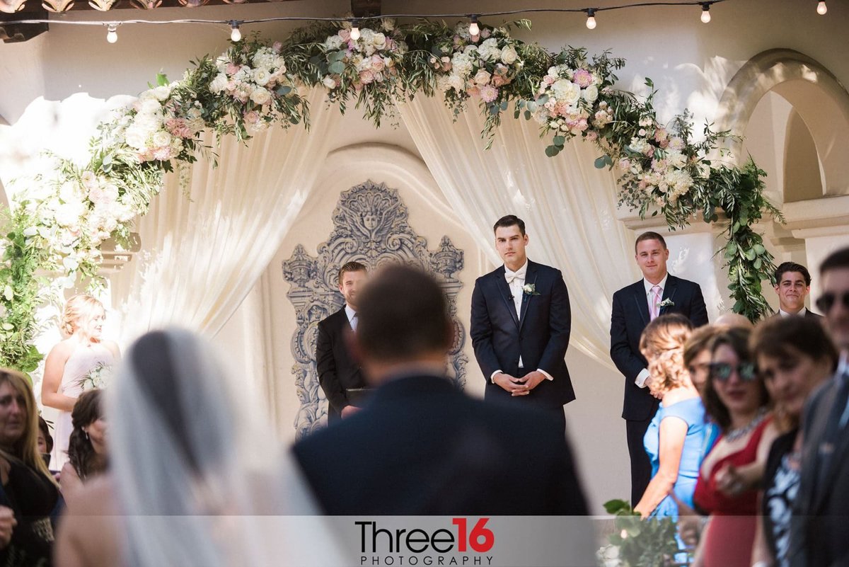 Groom watches his Bride walk up the aisle with her father