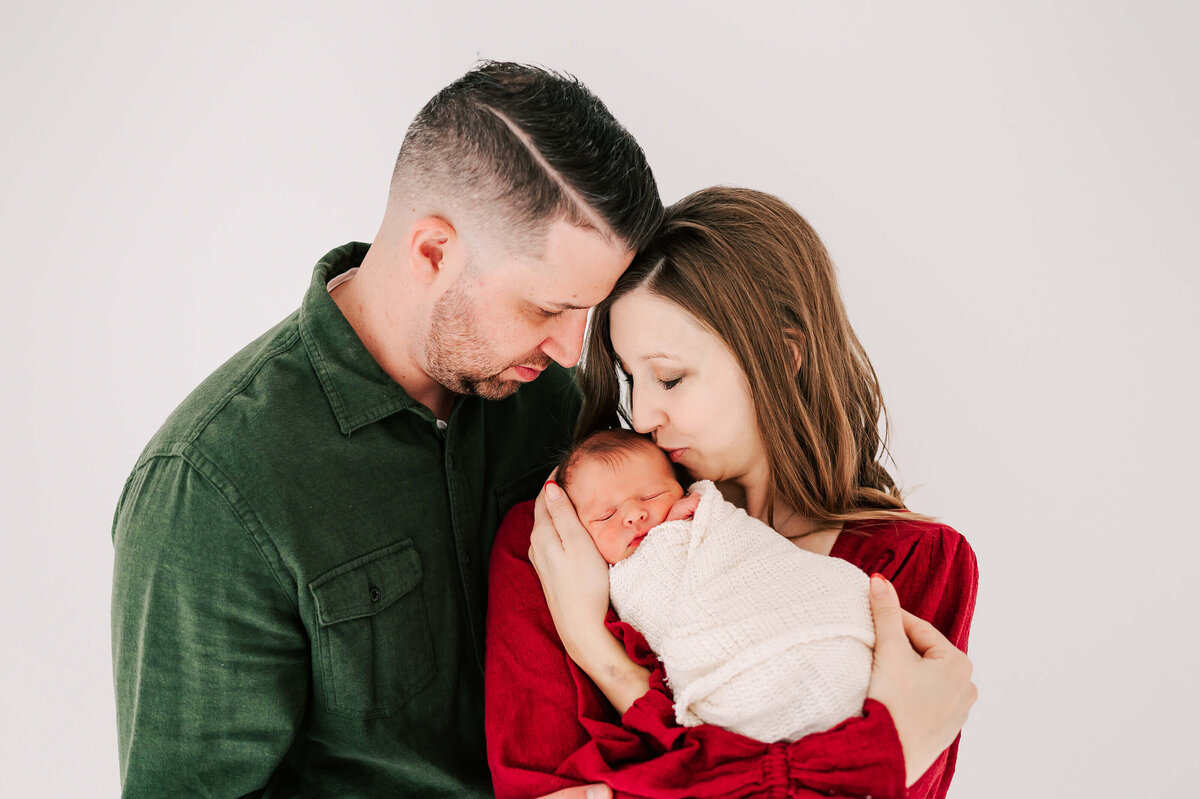 Springfield MO newborn photographer Jessica Kennedy of The XO Photography captures parents kissing sleeping newborn baby boy