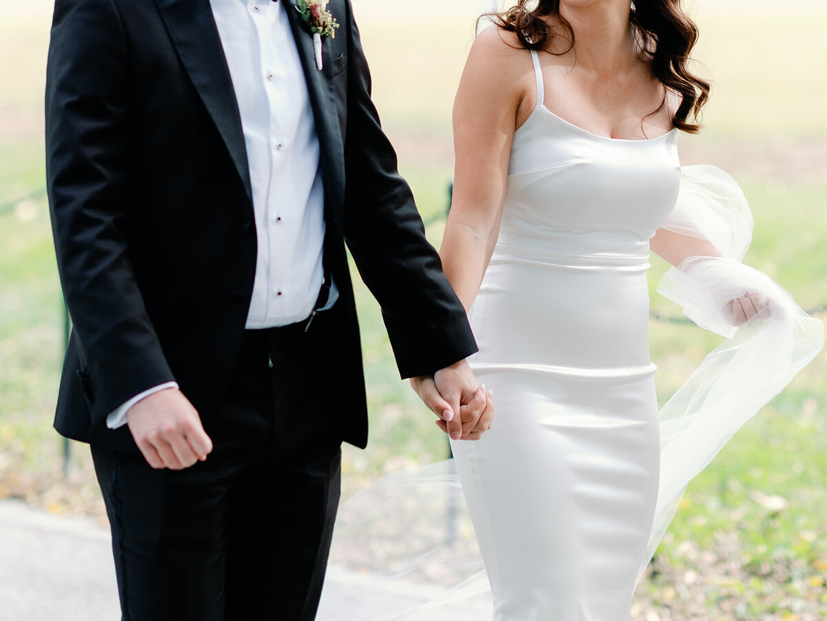 Photo of bride and groom holding hands as they walk.