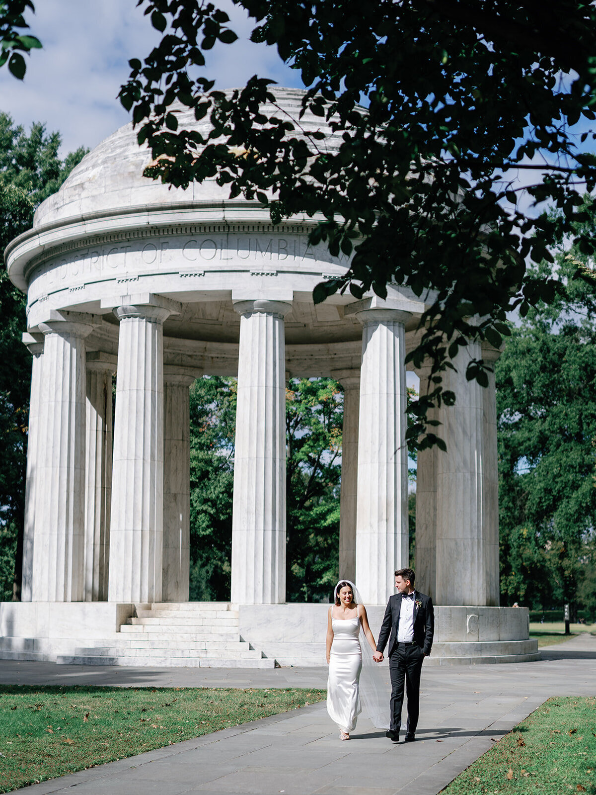 Bride and groom walking and holding hands by DC war memorial