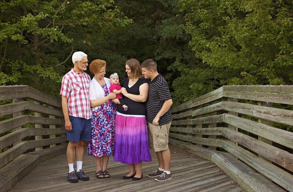 A picture of me with my mom, dad, husband, and daughter standing on a bridge at the park.