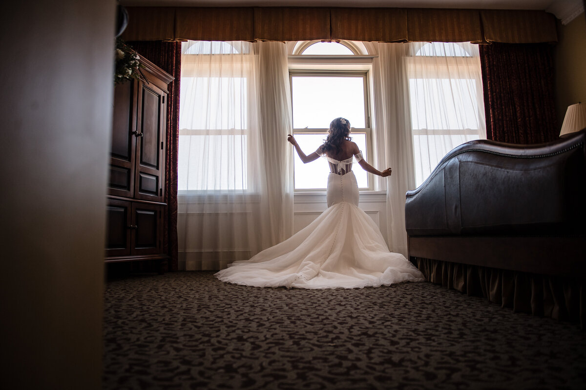 bride in hotel suite framed by window sill
