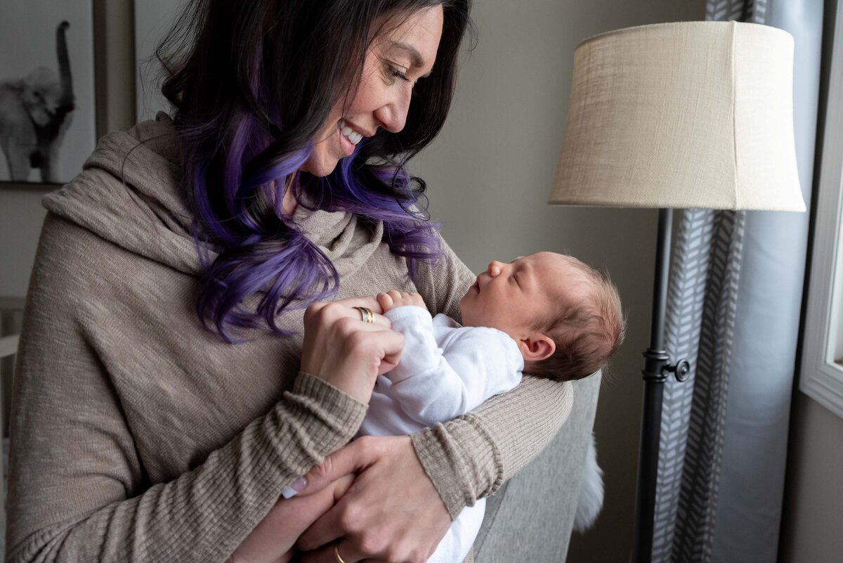 mom with purple hair smiling at baby