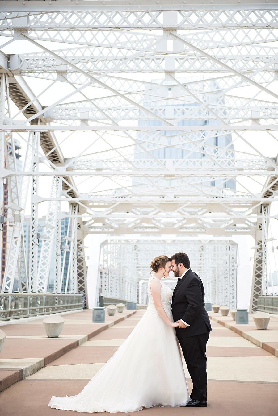 Couple facing each other, holding hands and smiling standing on the pedestrian bridge in Nashville