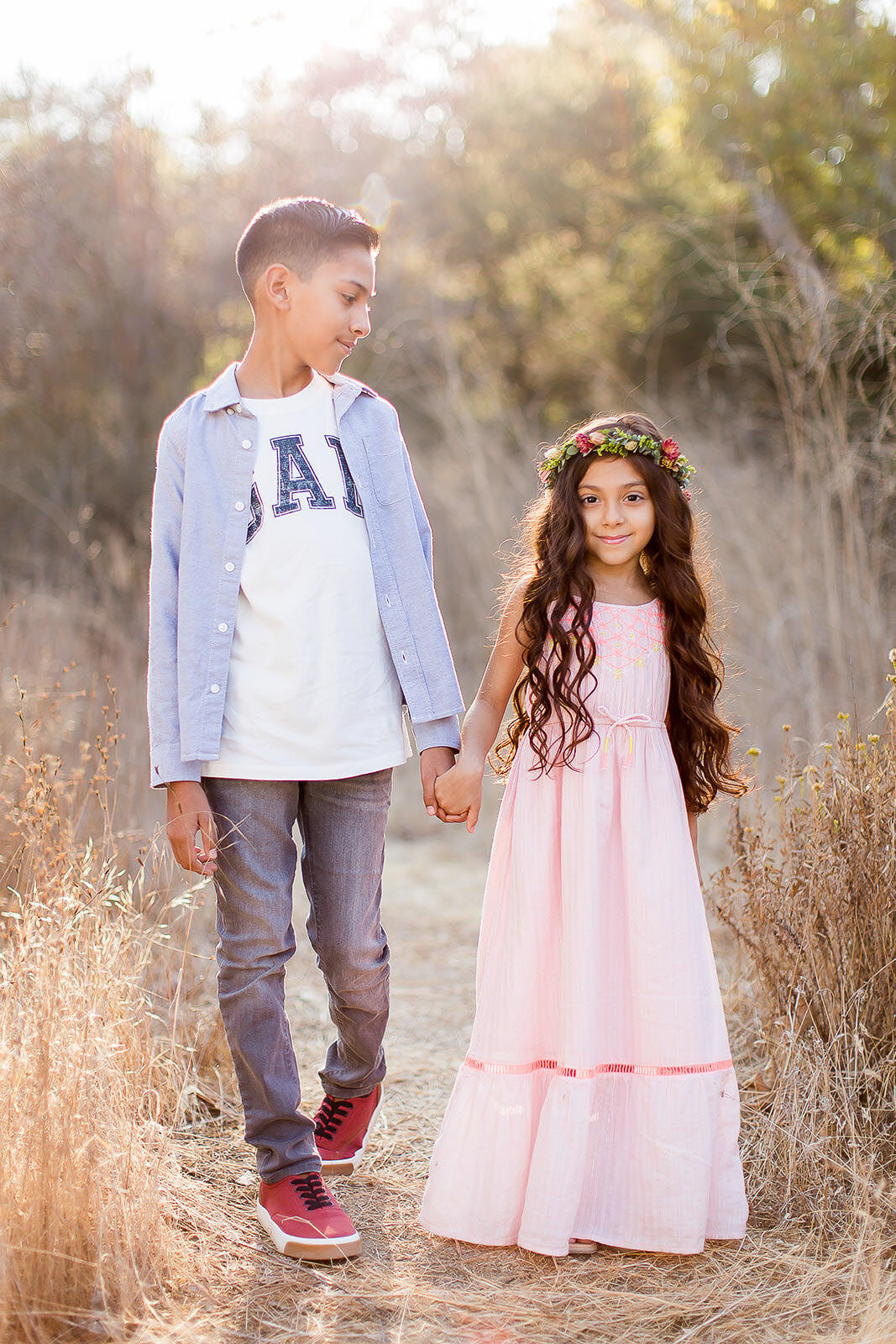 brother and sister holding hands walking through field