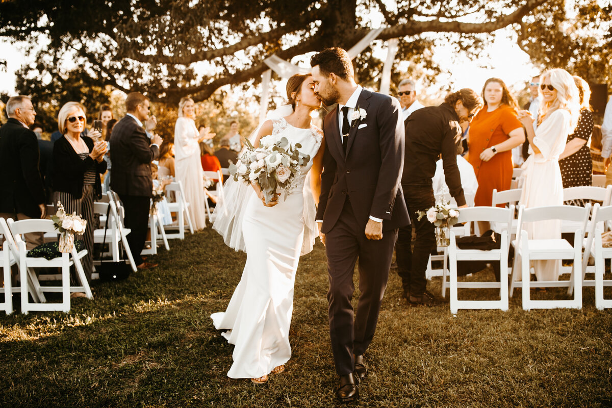 bride and groom celebrate kissing walking down the aisle after ceremony