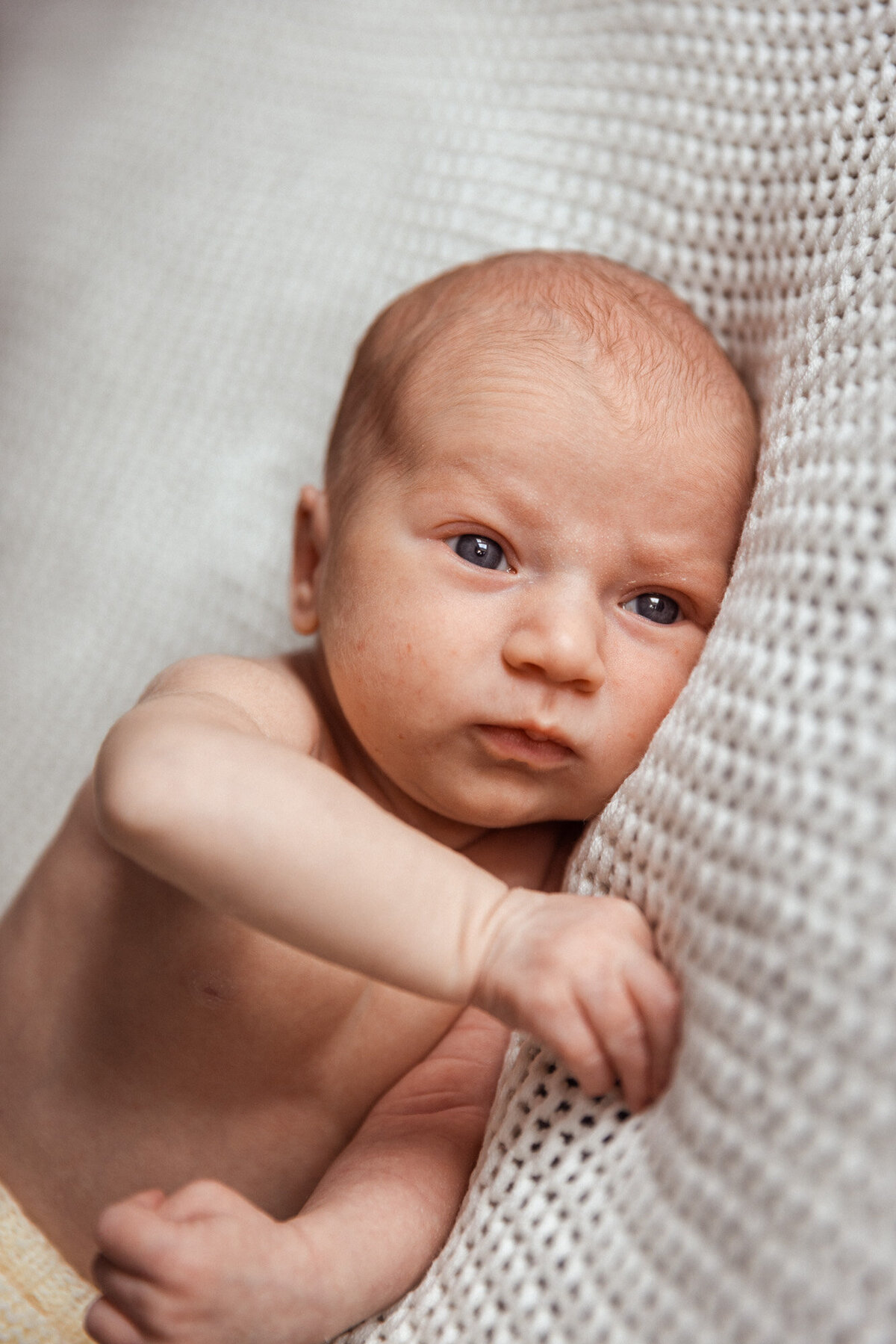 Livsstilsfoto nærbilde av en baby som ligger på et hvitt pledd.