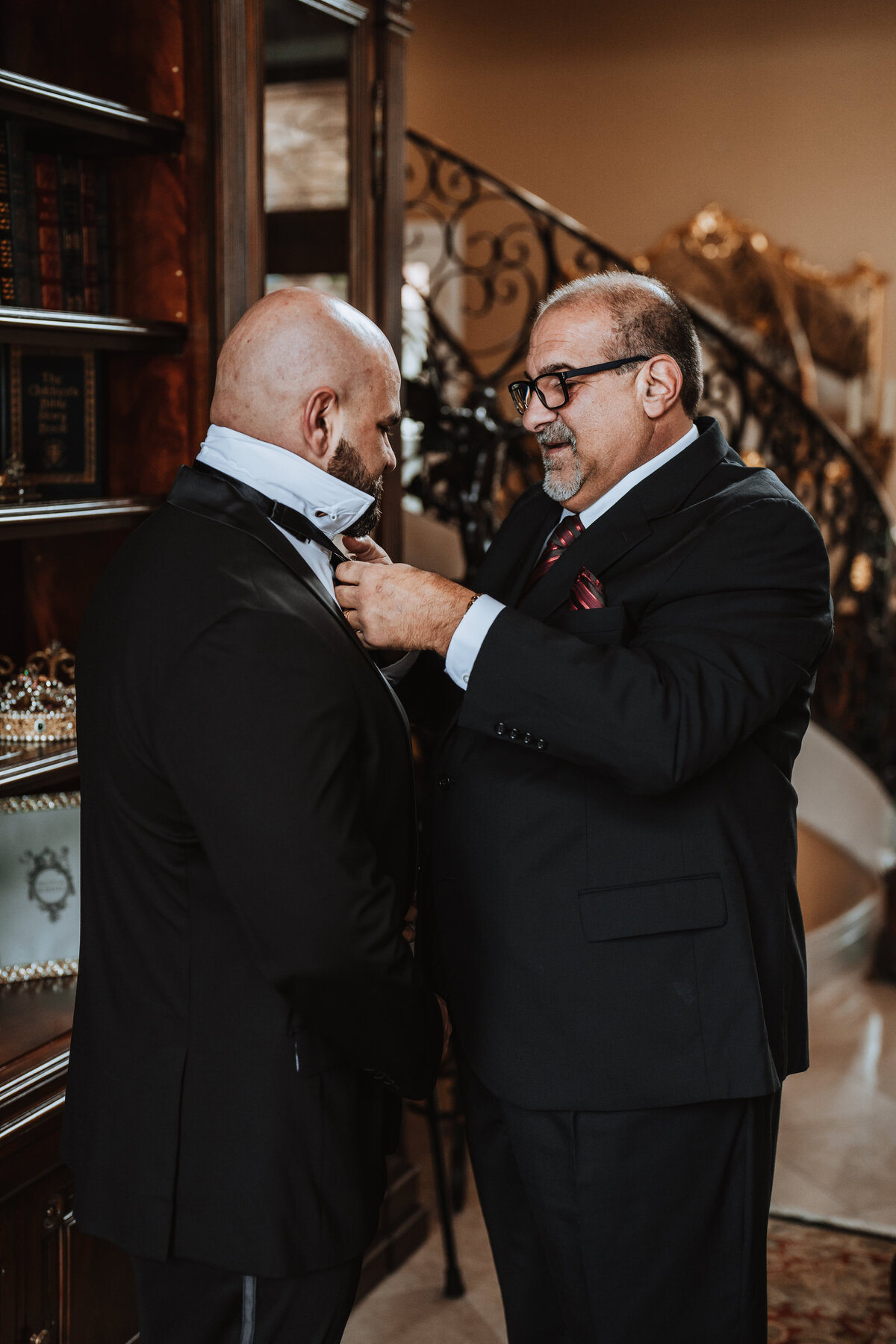 dad helping his son the groom put on his bowtie