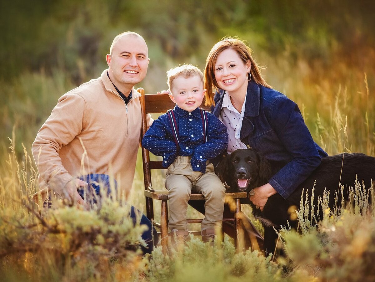 Fall colors in Laramie surround a family wearing tan and blue with an adorable little boy in suspenders.