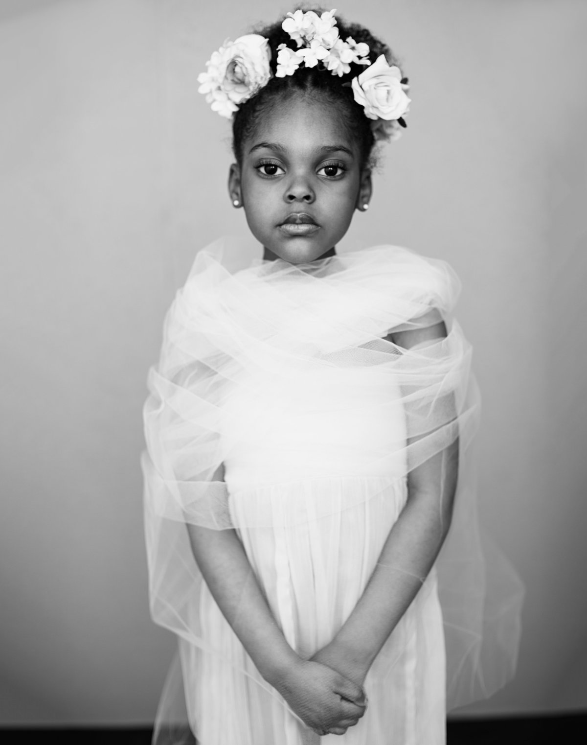 An African American black girl with a flower crown looks into the camera as she poses for a black and white portrait taken at Janel Lee Photography studios in Cincinnati