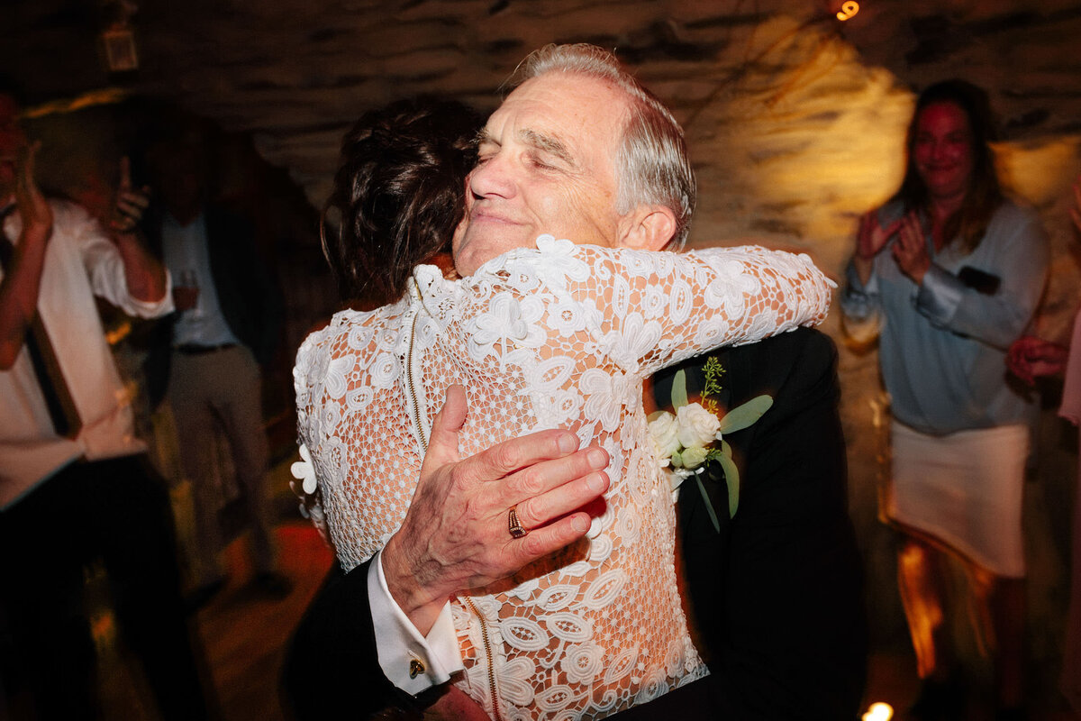 father of bride hugging daughter in white dress at wedding reception dance
