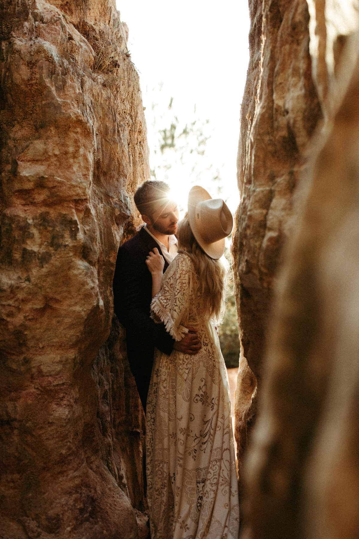 Boho bride and groom about to kiss in slot canyon as sun shines through