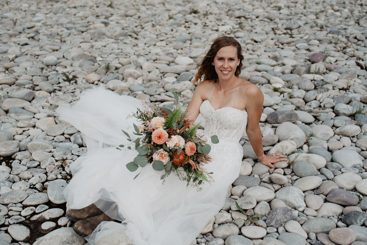 Jackson Hole Photographers capture bride sitting on rocks after Grand Teton wedding