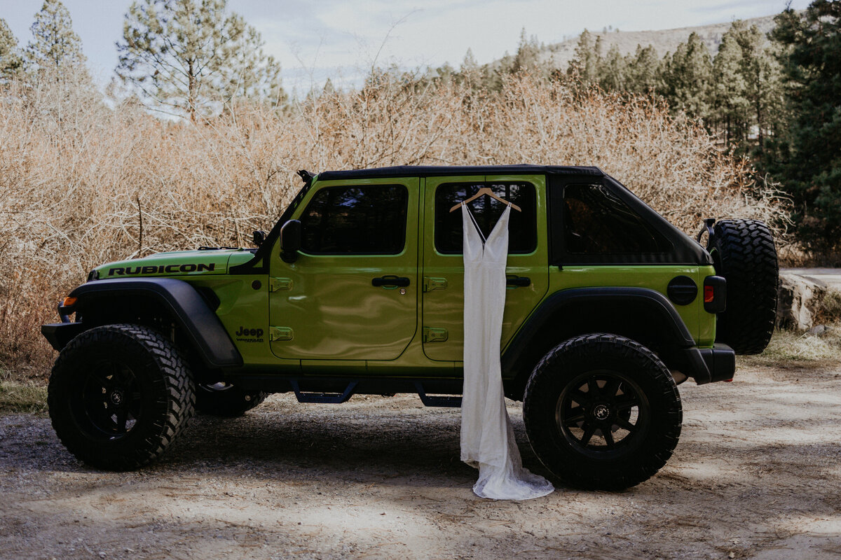 lace wedding dress hanging on green jeep wrangler