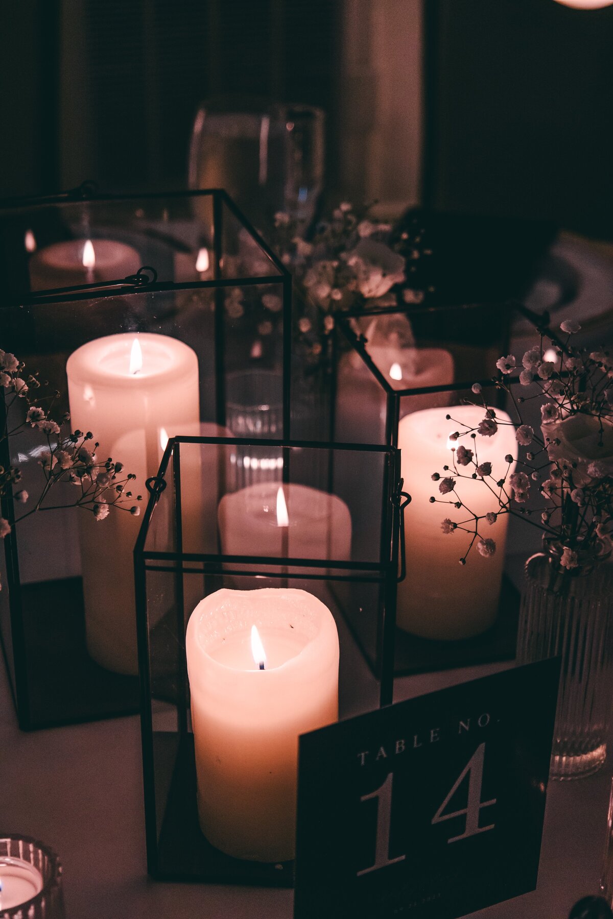 Elegant table setting featuring lit candles in glass holders, floral accents, and a "table no. 14" sign on a dimly lit background, perfect for events in Davenport.