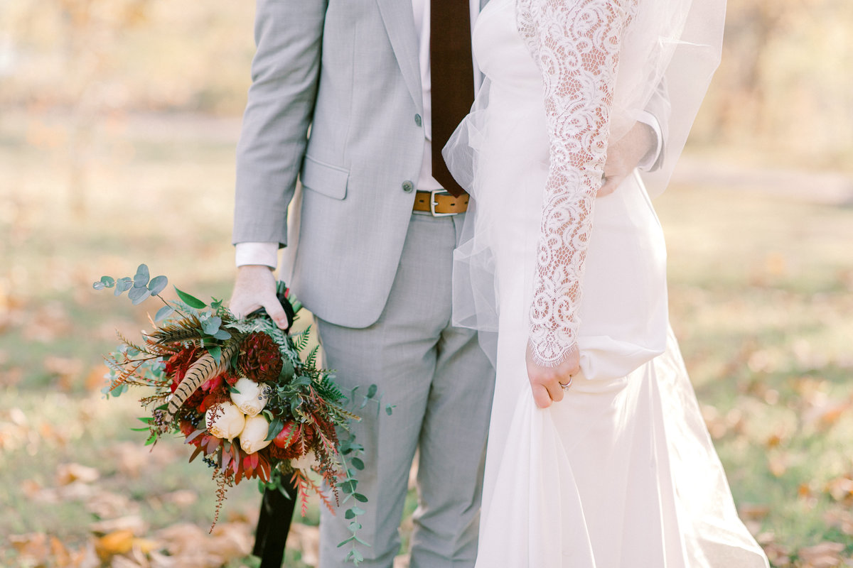 Groom in grey suit holding bridal bouquet