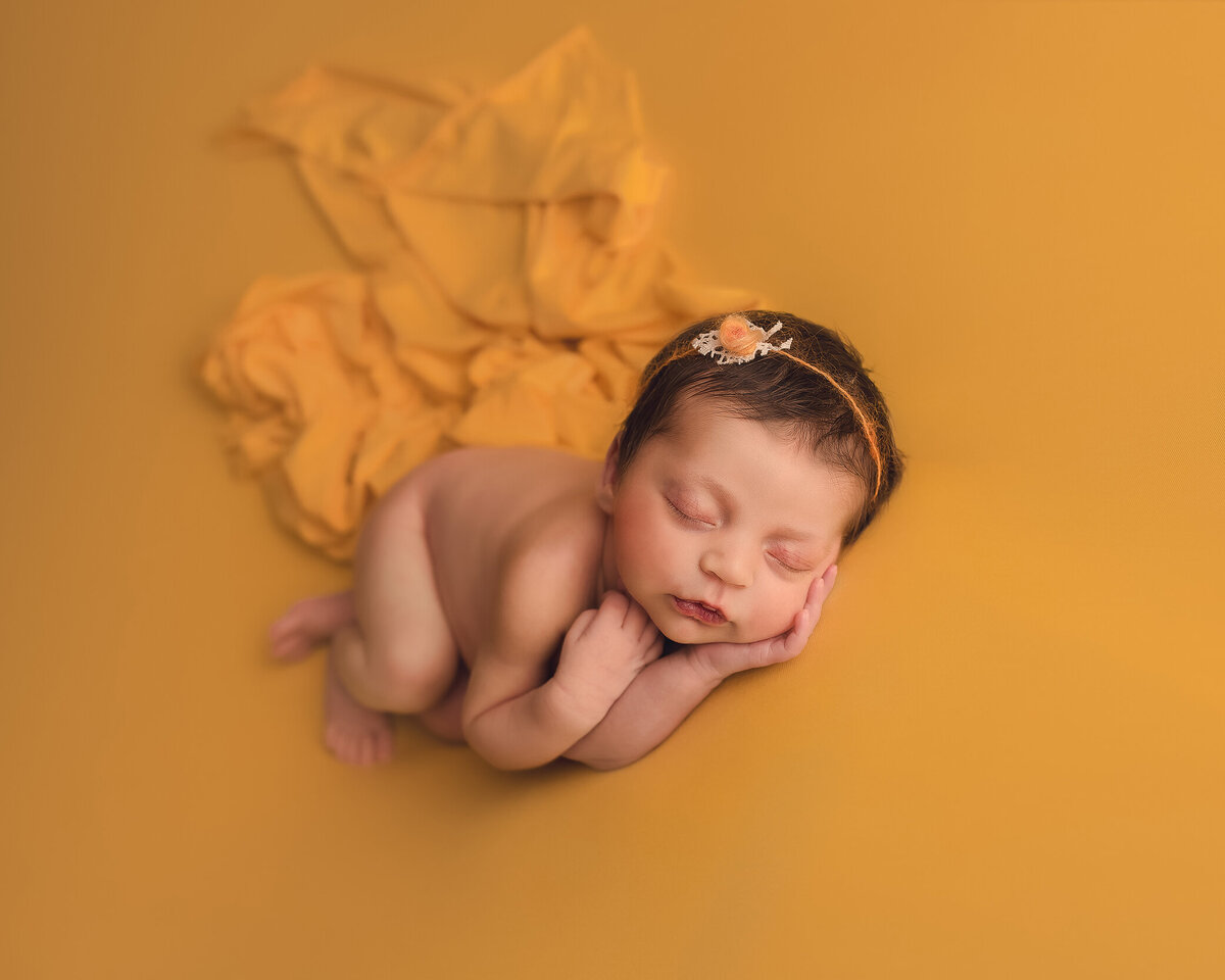 Sleeping newborn safely posed on yellow, Katie Anne