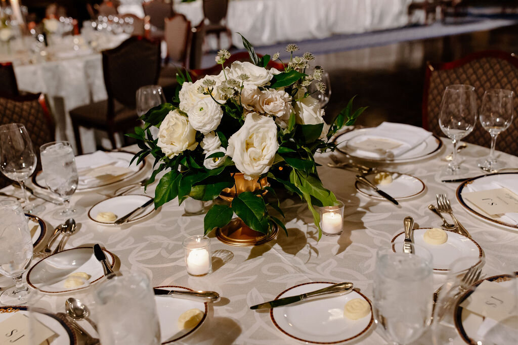 Sophisticated gold and ceramic tableware with classic white rose centerpieces sit on table at Union League Club of Chicago wedding reception.