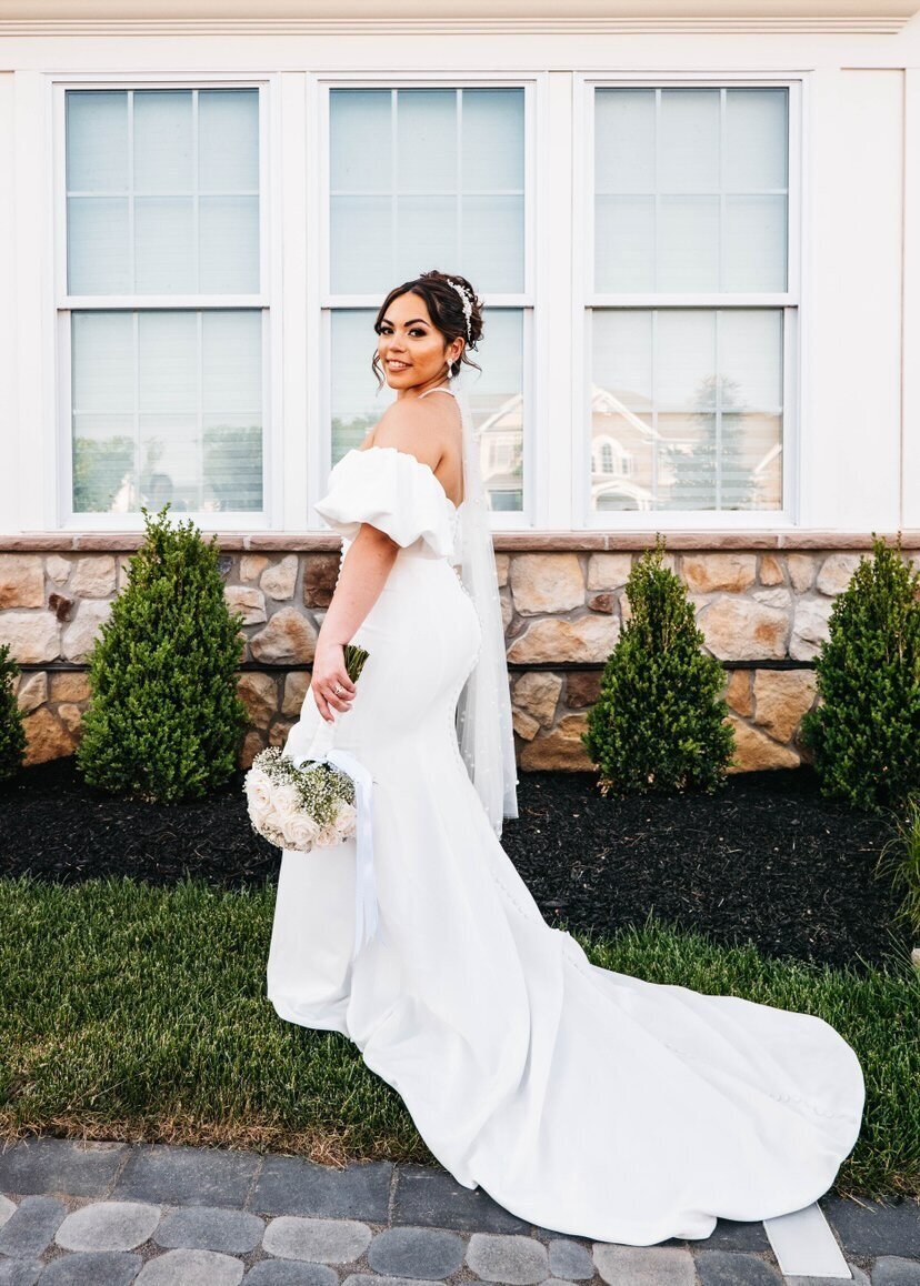 A pretty latin bride wearing a wedding dress and holding a bouquet in an elegant garden.