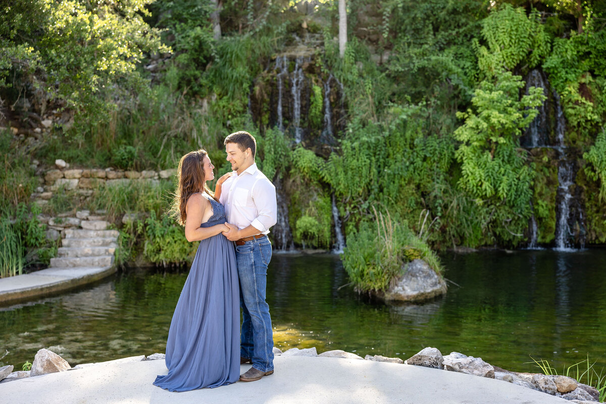 wedding engagement session in long blue dress with sunrise green foliage and waterfall at Remi's Ridge Hidden Falls in Spring Branch Texas