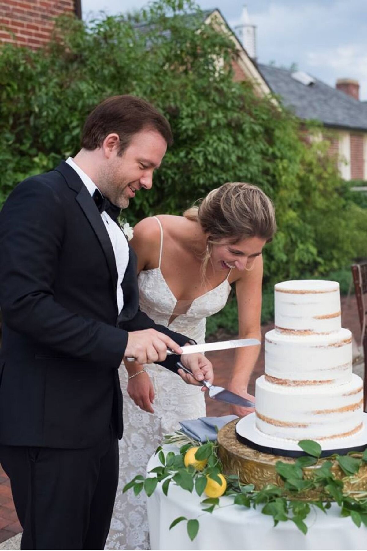 Bride and groom cut their wedding cake with lemon and greenery accents at their luxury Italian inspired Chicago North Shore wedding.