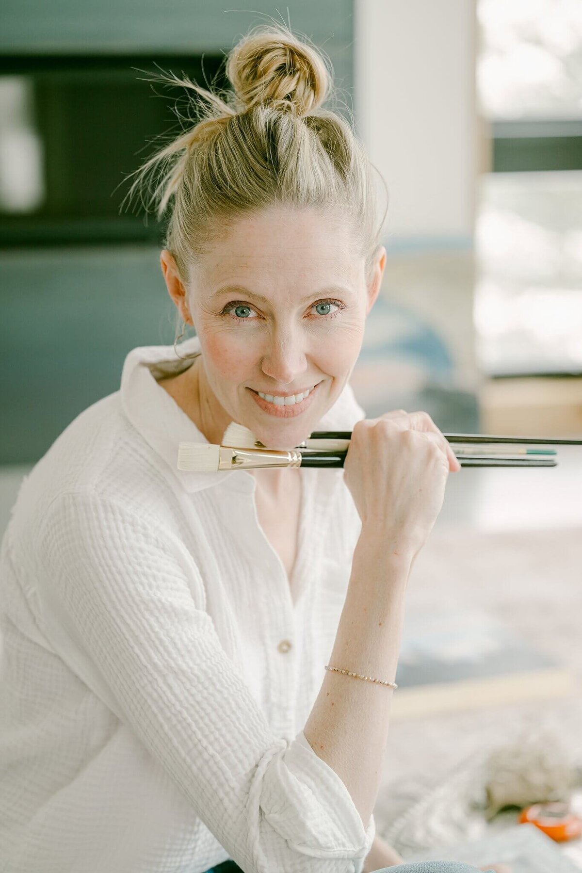painter headshot looking at camera holding her paintbrushes