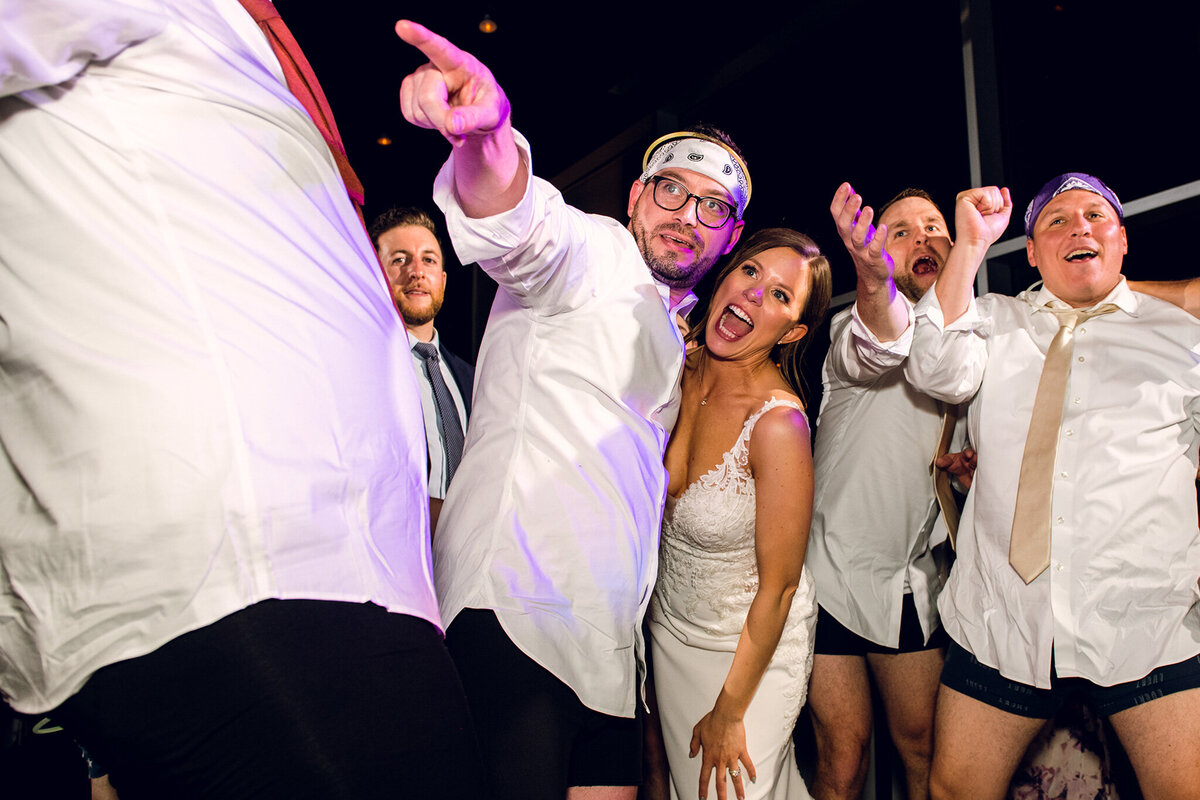 A group of bridesmaids and grooms dancing at a wedding.