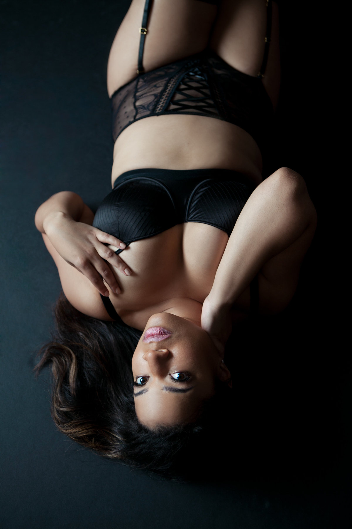 Color Image image taken in a New York City Photography Studio by a boudoir photographer. Black bra and panty lingerie set with garters on a black background