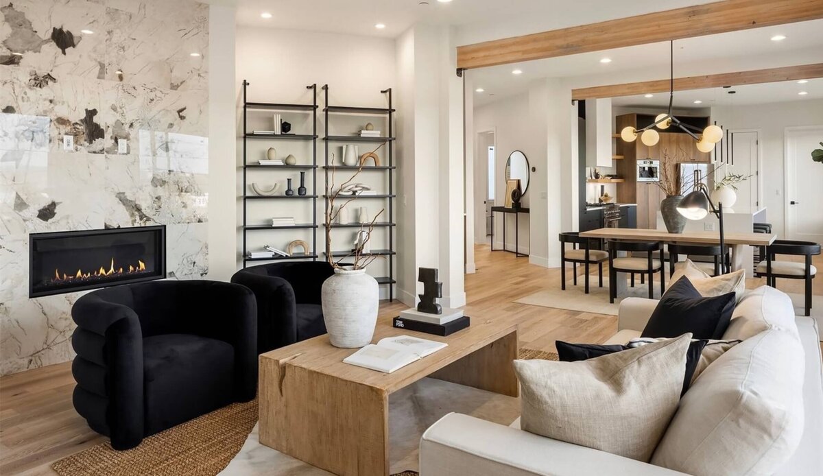 luxury real estate living room marble fireplace with black modern velvet club chairs and solid  wood coffee table and iron built in bookshelves