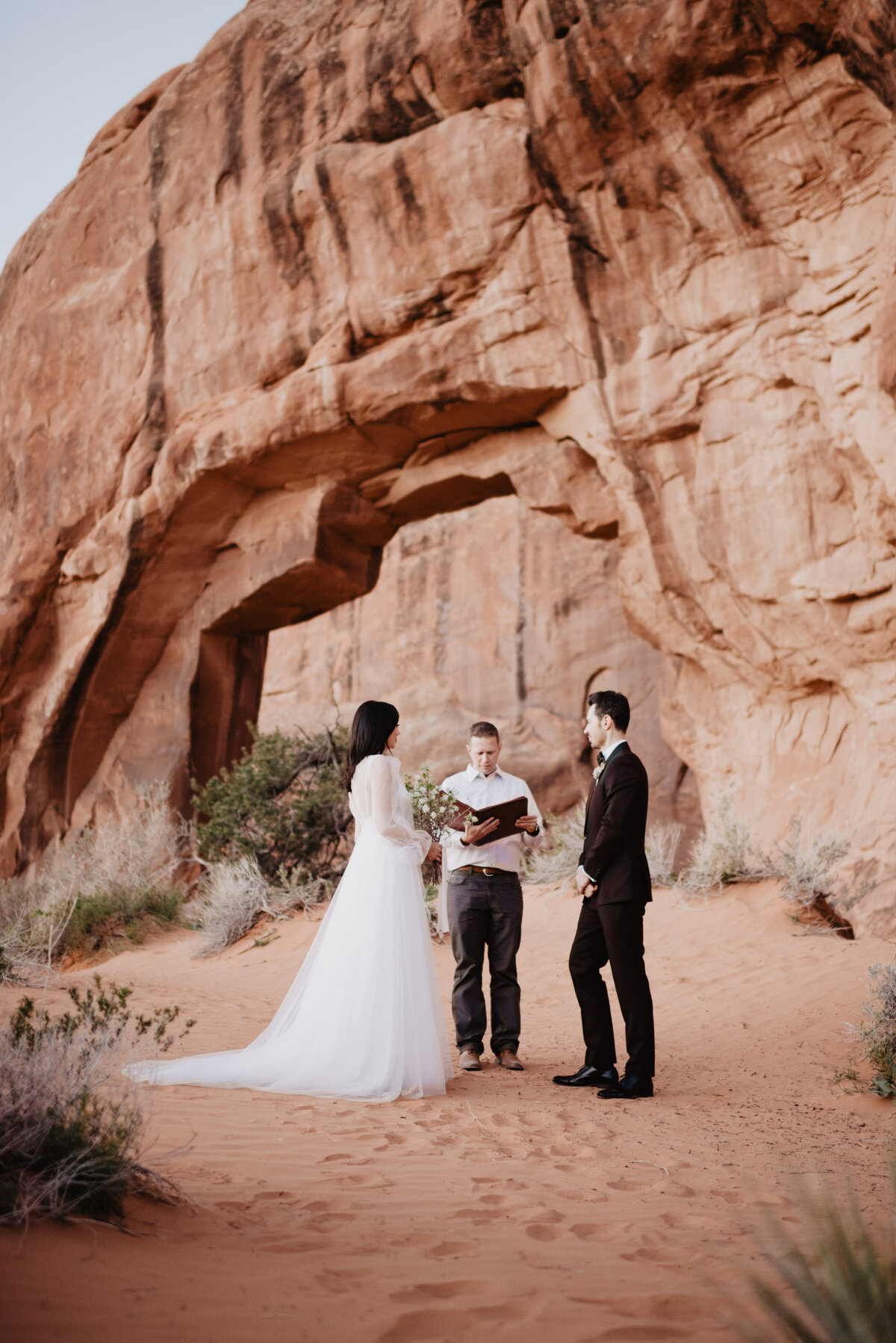 Utah elopement photographer captures bride and groom standing in Arches National Park during wedding ceremony