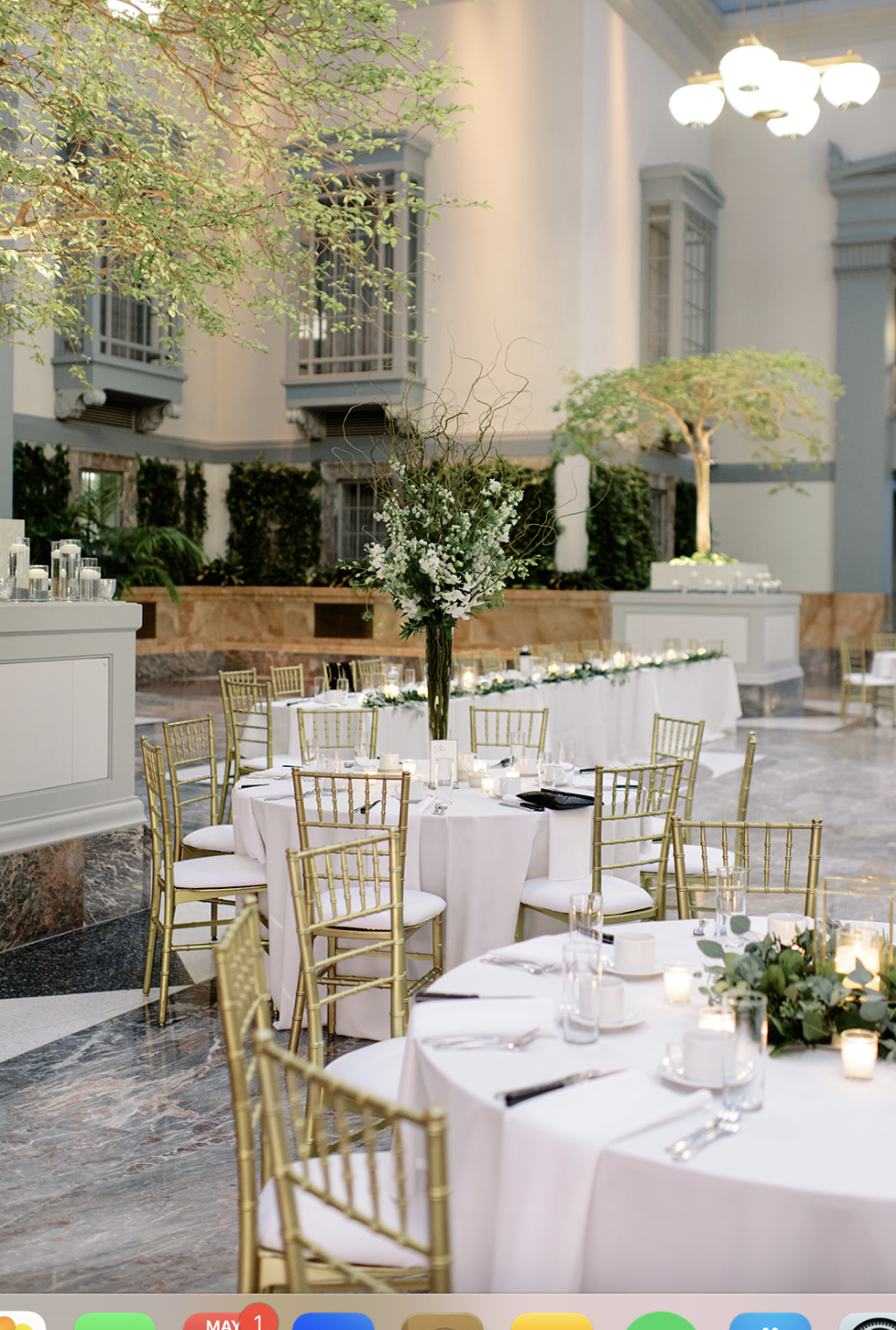 Gold chairs surround round tables with minimalist greenery centerpieces at lush Chicago wedding reception.