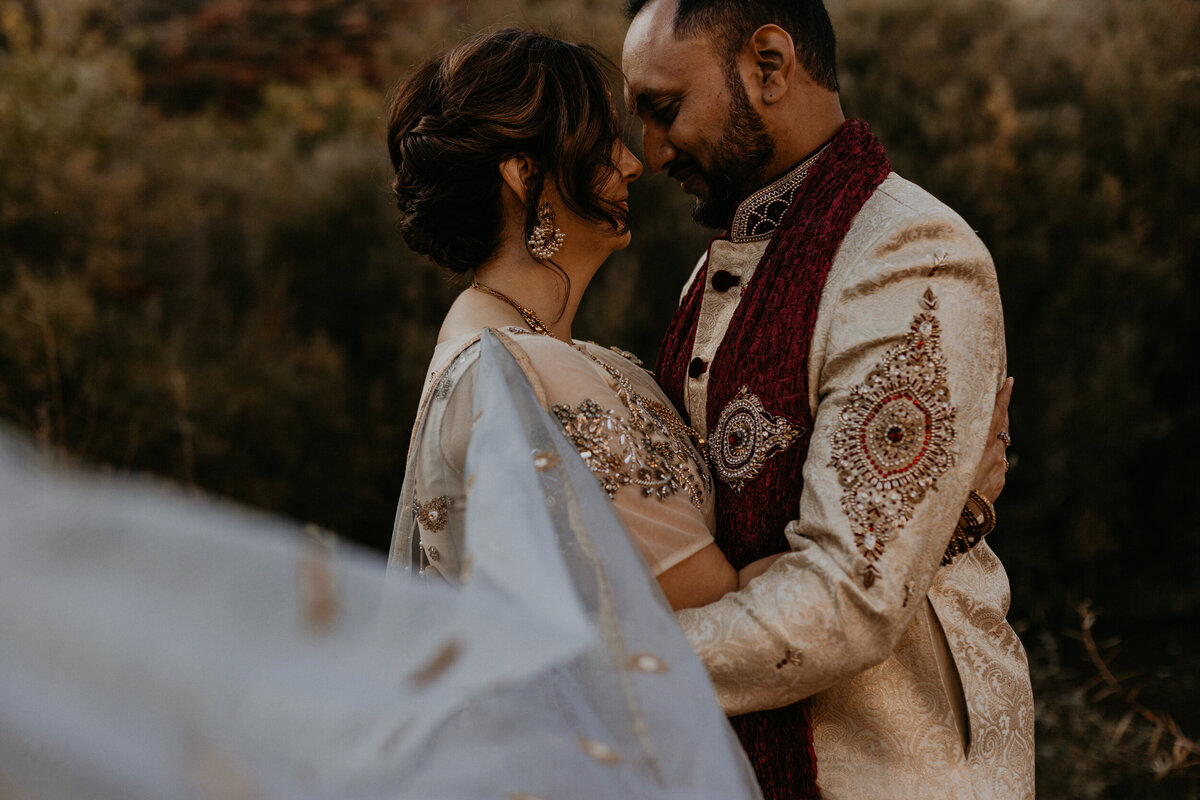 bride and groom holding each other with their Indian attire and jewelry